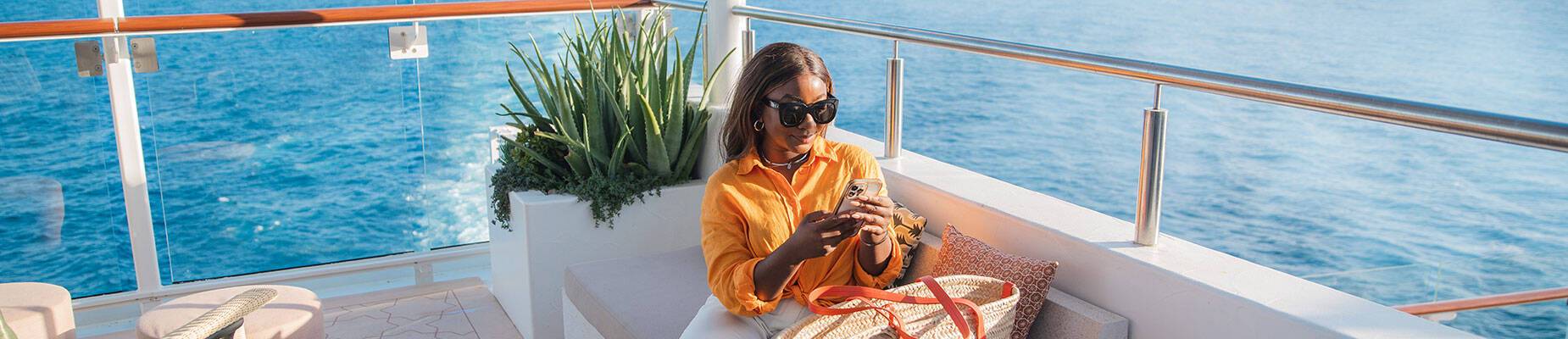 Person sitting on their phone on a cruise ship deck