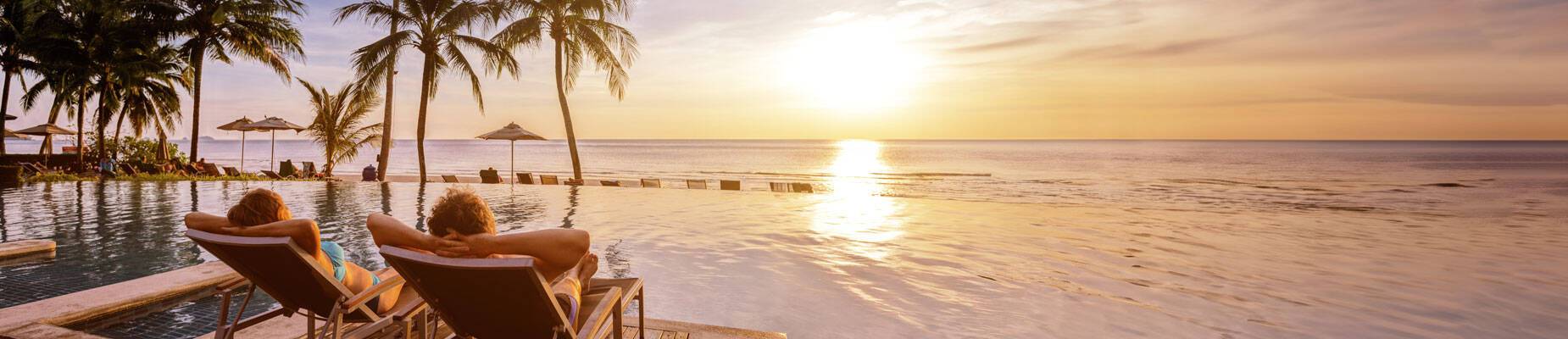 Panoramic image of a couple relaxing watching the sunset on holiday