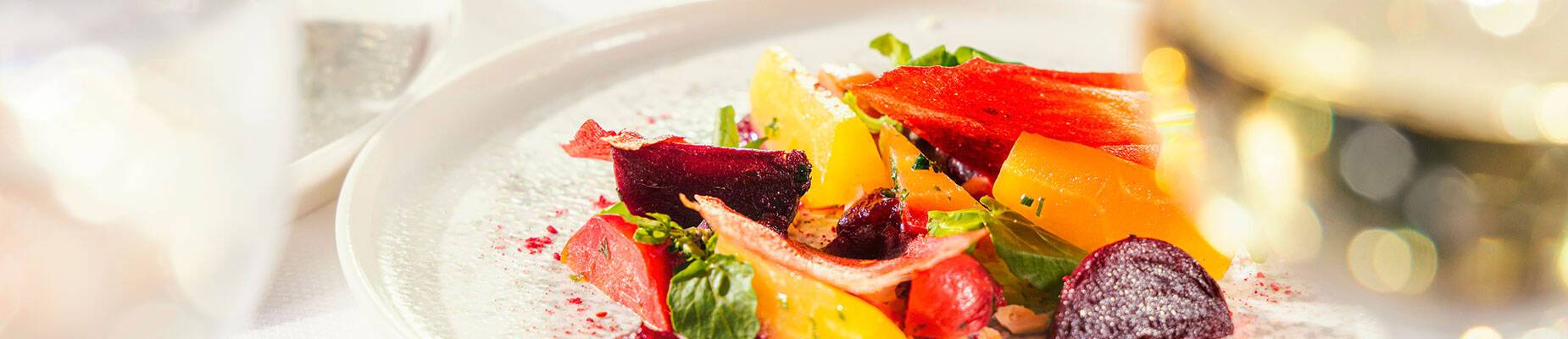 Two meals and a glass of wine on a table covered with a white linen tablecloth