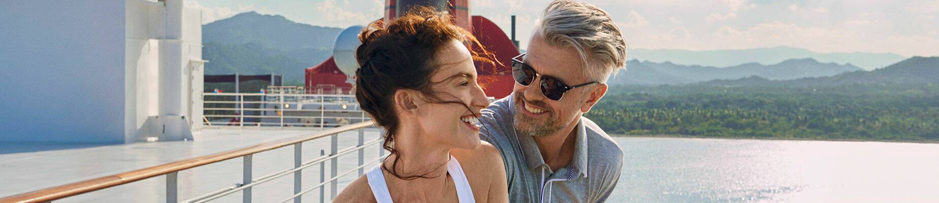 Male and female couple on a cruise ship deck looking out at sea