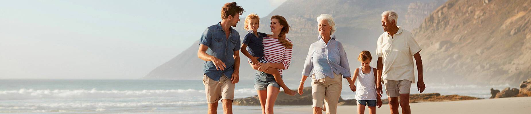 A multigenerational family walking along a beach