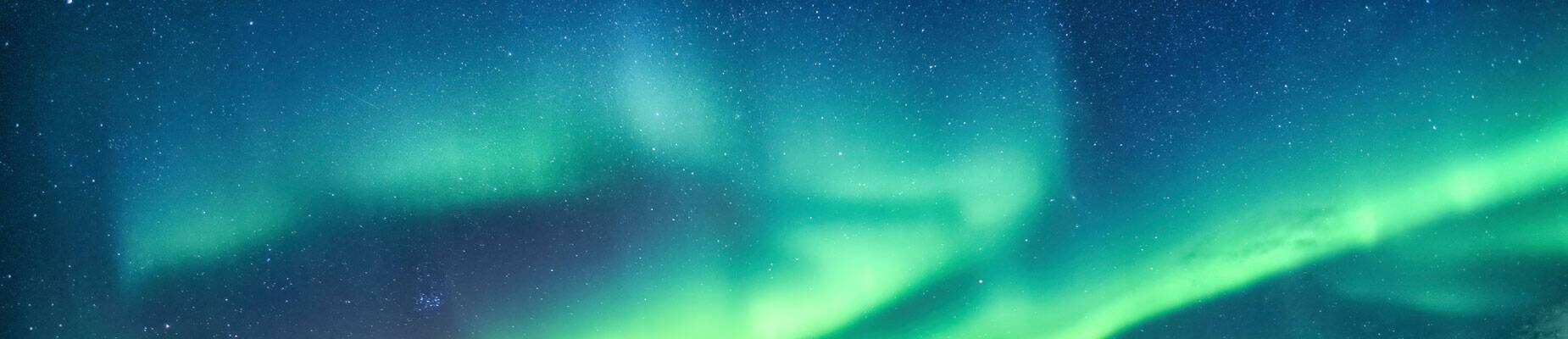 A panoramic image of the Northern Lights in the night sky in Norway