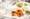 Two meals and a glass of wine on a table covered with a white linen tablecloth