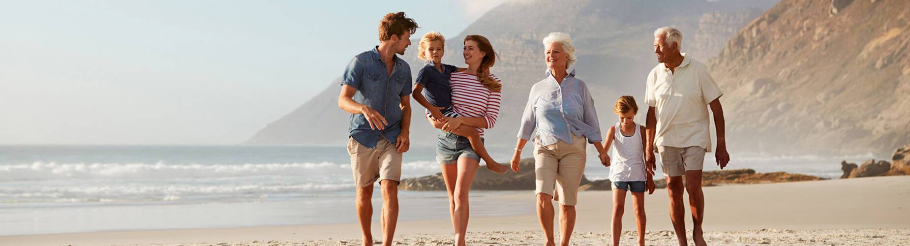 A multigenerational family walking along a beach